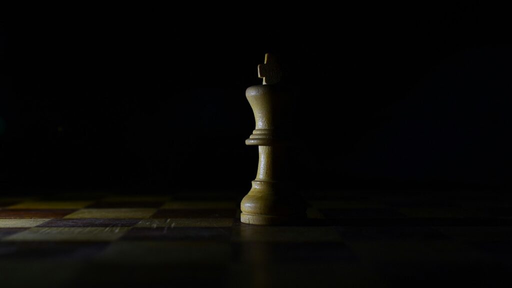 pion du roi de jeu d'échec couleur ivoire à moitié dans l'ombre