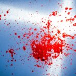 projection de sang sur une vitre bleutée éclairée par un rayon de soleil