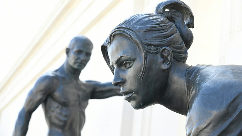deux statues de bronze, au premier plan la tête d'une jeune femme, au second plan, un homme plus âgé